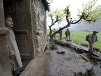 In this file photo taken on April 8, 2009, an Afghan boy watches US soldiers from 1st Infantry Division patrolling in a village during a mission of searching weapon cache in Nishagam, in Afghanistan's eastern Kunar province. American forces have started pulling out of two bases in Afghanistan, a US official said on March 10, 2020 the day peace talks between Kabul and the Taliban were due to start despite widespread violence and a political crisis. The United States is keen to end its longest-ever conflict, 