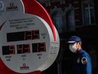 A security guard wearing a face mask walks in front of the Olympic countdown clock outside Tokyo station on March 11, 2020. Japan and Olympic organisers are at pains to insist this summer's Games in Tokyo are on, despite the new coronavirus outbreak. Philip FONG / AFP