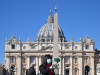 A photo taken on March 11, 2020 shows a tourist wearing a protective mask taking a selfie photo by the Vatican's Saint Peter's Square and its main basilica, a day after they were closed to tourists as part of a broader clampdown aimed at curbing the coronavirus outbreak. ANDREAS SOLARO / AFP