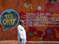 A man walks past a graffiti with a positive message painted on a wall in a street in Mumbai on March 14, 2020. INDRANIL MUKHERJEE / AFP