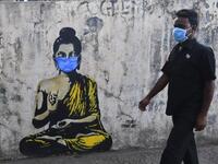 A resident wearing a facemask amid concerns over the spread of the COVID-19 novel coronavirus walks past a graffiti of Buddha wearing facemask, in Mumbai on March 16, 2020. INDRANIL MUKHERJEE / AFP