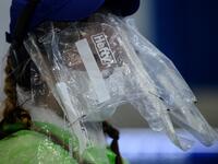 A passenger wears a face mask and plastic food bags on her face as a precautionary measure against the COVID-19 coronavirus after landing at Hong Kong’s international airport on March 19, 2020. On March 18, Hong Kong authorities began ordering all arrivals from overseas to wear electronic bracelets, connected to an app to mark your location, and two weeks self-quarantine. ANTHONY WALLACE / AFP
