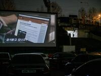 In a photo taken on March 21, 2020 a screen shows a movie at a drive-through cinema in Seoul. Box office numbers in South Korea -- which has 8,897 confirmed virus cases -- have plummeted in recent weeks due to the epidemic, with authorities urging the public to avoid large crowds. But at drive-in cinemas, moviegoers can enjoy a movie from the comfort of their cars, parked in front of a large outdoor screen.  Ed JONES / AFP