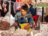 Elderly woman chops blocks of nougat at a market in Portugal (Shutterstock) 