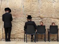 Children sit in chairs next to ultra-Orthodox Jewish men praying at the nearly deserted Western Wall, the holiest site where Jews can pray, after Israel has imposed some of the world's tightest restrictions to contain COVID-19 coronavirus disease, in Jerusalem on March 12, 2020. Israel imposed a two-week quarantine on all travellers entering the country, almost stopping tourism and limiting public gatherings as officials confirmed its 100th case of the COVID-19 coronavirus disease. Emmanuel DUNAND / AFP