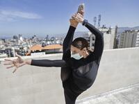 Sherazade Mami, a 28-year-old Tunisian professional dancer and performer at the Caracalla dance theatre and a teacher at the Caracalla dance school, practices while wearing a surgical mask on the roof of her apartment building in the suburb of Dekwaneh on the eastern outskirts of Lebanon's capital Beirut on April 4, 2020.  JOSEPH EID / AFP