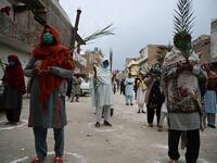 Christian devotees stand in circles marked on the ground to maintain social distancing as they hold palm branches to celebrate a Palm Sunday service at the Christian neighborhood during a government-imposed nationwide lockdown as a preventive measure against the COVID-19 coronavirus, in Islamabad on April 5, 2020.  Aamir QURESHI / AFP