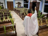 A Roman Catholic priest blesses palm branches occupying church pews during Palm Sunday event in Borongan town, Eastern Samar province, central Philippines on April 5, 2020. Alren BERONIO / AFP