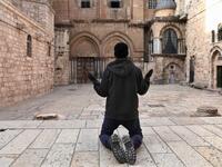 A Christian worshipper kneels in prayer facing the shut doors of the Church of the Holy Sepulchre in Jerusalem's Old City on April 7, 2020, amid the COVID-19 pandemic. All cultural sites in the Holy Land are shuttered, regardless of their religious affiliation, as authorities seek to forestall the spread of the deadly respiratory disease, which will prevent Christians from congregating for the Easter service, this coming Sunday for Catholic worshippers, then a week later on April 19 for Orthodox Easter. GAL