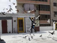 A pigeon owner, wearing personal protective equipment, trains his pigeons on the rooftop of his building in the southern suburb of Beirut on April 11, 2020. ANWAR AMRO / AFP