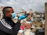 A pigeon owner, wearing personal protective equipment, poses with a pigeon on the rooftop of his building in the southern suburb of Beirut on April 11, 2020. ANWAR AMRO / AFP