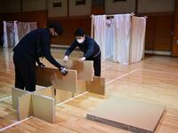 This photo taken on April 14, 2020 shows workers from Voluntary Architects' Network building partitions and beds at a shelter provided by Kanagawa prefecture for people who can’t afford to rent an apartment and used to stay at designated internet cafes, which are closed due to the COVID-19 coronavirus outbreak state of emergency, at a judo sport hall in Yokohama, Kanagawa prefecture. CHARLY TRIBALLEAU / AFP
