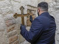 A Christian worshipper wearing a face mask, due to the COVID-19 coronavirus pandemic, touches one of the stations of the Via Dolorosa (Way of Sorrow), the path traditionally believed to have been taken by Christ while on the way to be crucified, to receive a blessing, in the old city of Jerusalem on Orthodox Holy Friday April 17, 2020. AHMAD GHARABLI / AFP