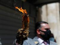 A man wearing a protective mask holds up candles lit from the Holy Fire in the church of the Holy Sepulchre, as very few Orthodox Christians gather in Jerusalem's Old City to celebrate Easter due to the lockdown imposed by authorities in a bid to limit the spread of the novel coronavirus, on April 18, 2020. Ahmad GHARABLI / AFP