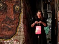 A woman lights a candle with a "Holy Fire" from small candles left on a path outside the Metochion (embassy church) of the Holy Sepulchre in Athens, where the Holy Light was brought earlier today from Jerusalem for the resurrection service on April 18, 2020 as part of the Orthodox Easter celebrations. The strict quarantine measures against the spread of the COVID-19 (the novel coronavirus) keeps churches empty during the Orthodox Easter services and faithfuls are not allow to light their candles with the Ho