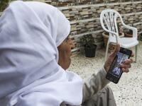 A Palestinian woman watches on her phone a sermon recorded and broadcast by a preacher from an empty mosque, due to the COVID-19 coronavirus pandemic, in the village of Salem east of Nablus in the occupied West Bank on the first Friday of the Muslim holy month of Ramadan on April 24, 2020. JAAFAR ASHTIYEH / AFP