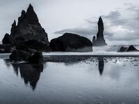 Rock formations on a black sand beach in Iceland with reflection in the Sea and a dark sky in misty moody weather with dark colors and a rough sea (Shutterstock)