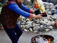 In this picture taken on March 17, 2020, a woman holds her new Taoist god statue above a fire during a blessing ceremony after it was restored by sculptor Lin Hsin-lai at his workplace in Taoyuan, northern Taiwan. Every spare surface of Lin Hsin-lai's four-storey shop is crammed with a pantheon of Taiwan's celestial beings, testament to the decades he has spent sheltering and restoring unwanted statues of gods.  Sam Yeh / AFP