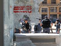 Members of the Lebanese security forces are seen through a broken store window in the downtown area of the capital Beirut, during an anti-government demonstration marking International Workers' Day (Labour Day), on May 1, 2020. ANWAR AMRO / AFP