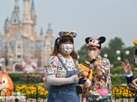 People wearing face masks visit the Disneyland amusement park in Shanghai on May 11, 2020. Disneyland Shanghai reopened on May 11 to the public after being closed since January due to the COVID-19 coronavirus outbreak. Hector RETAMAL / AFP