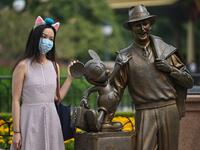 A woman wearing a face masks visits the Disneyland amusement park in Shanghai on May 11, 2020. Disneyland Shanghai reopened on May 11 to the public after being closed since January due to the COVID-19 coronavirus outbreak. Hector RETAMAL / AFP
