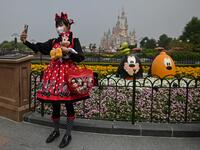 A woman wearing a face mask takes a selfie while visiting the Disneyland amusement park in Shanghai on May 11, 2020. Disneyland Shanghai reopened on May 11 to the public after being closed since January due to the COVID-19 coronavirus outbreak. Hector RETAMAL / AFP