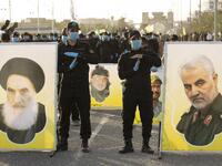 Members of the Hashed al-Shaabi (Popular Mobilisation) paramilitary force stand near portraits of Iraq's top Shiite cleric Grand Ayatollah Ali Sistani (L) and slain Iranian general Qasem Soleimani (R) during a military parade in the southern Iraqi city of Basra on June 14, 2020, marking the sixth anniversary of its founding after Sistani called to defend the country from the Islamic State group (IS). Hussein FALEH / AFP