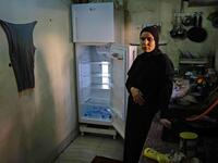 A Lebanese woman stands next to her empty refrigerator in her apartment in the port city of Tripoli north of Beirut on June 17, 2020. Lebanon's economic crisis has led to a collapse of the local currency and purchasing power, plunging whole segments of the population into poverty as exemplified by near-empty fridges in many households. IBRAHIM CHALHOUB / AFP