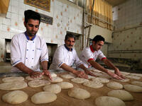 Iranian bakers Farzad Rabiei (L), 30, Esmail Asghari, 66, and Mojtaba Haydari, 23, prepare dough for Barbari bread in Tehran on June 7, 2020. ATTA KENARE / AFP