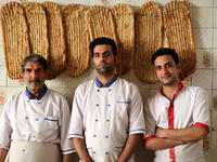 Iranian bakers Esmail Asghari, 66, Farzad Rabiei, 30, and Mojtaba Haydari, 23, pose with Barbari bread in Tehran on June 7, 2020. ATTA KENARE / AFP