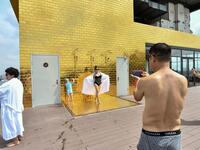 Guests pose for photographs at the infinity pool of the newly-inaugurated Dolce Hanoi Golden Lake hotel, the world's first gold-plated hotel, in Hanoi on July 2, 2020. Manan VATSYAYANA / AFP