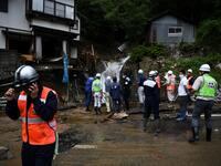 Government officials look at a damaged home following heavy rains and flooding in the village of Gero, Gifu prefecture on July 9, 2020. Japanese emergency services and troops were scrambling to reach thousands of homes cut off by devastating flooding and landslides that have killed dozens and caused widespread damage. Philip FONG / AFP