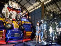 This photograph taken on July 18, 2020 shows children playing in front of a life-sized sculpture of a character from the "Transformers" film franchise made of scrap metal parts at the Ban Hun Lek museum in Ang Thong, some 100km north of Bangkok. "Ban Hun Lek" or "The House of Steel Robots" is a museum where a collective of artists display their scrap metal creations depicting popular comics and sci-fi film characters. Mladen ANTONOV / AFP