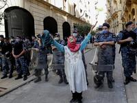 An elderly woman raises her arms in front of Lebanese security forces standing guard in front of the World Bank offices in the downtown district of the Lebanese capital Beirut on July 25, 2020, as demonstrators rally against the Bisri dam project, partly financed by the World Bank. The government says the Bisri dam is vital to tackling chronic water shortages. But activists say it will ravage most of the region's farmland and historic sites, and they also fear the consequences of building it on a seismic fa