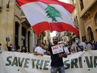 A man waves a large Lebanese national flag as he takes part in a protest in front of the World Bank offices in the downtown district of the capital Beirut on July 25, 2020, against the Bisri dam project, partly financed by the World Bank. The government says the Bisri dam is vital to tackling chronic water shortages. But activists say it will ravage most of the region's farmland and historic sites, and they also fear the consequences of building it on a seismic fault line.  ANWAR AMRO / AFP