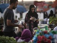 Relatives of a slain Kurdish fighter with the Syrian Democratic Forces (SDF), visit his tomb at a cemetery in the Kurdish-majority city of Qamishli of Syria's northeastern Hasakeh province, on the eve of the holy Muslim Feast of Sacrifice or Eid al-Adha on July 30, 2020. Delil SOULEIMAN / AFP