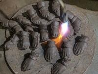 In this picture taken on August 15, 2020, an artisan uses a blowtorch to dry the hands of clay idols of elephant headed Hindu god Ganesha at Muslim potter Yusuf Zakaria Galwani's workshop at Kumbharwada inside the Dharavi slums in Mumbai. After the coronavirus pandemic clobbered his pottery business, a Muslim artisan from India's largest slum turned to a Hindu god to revive his fortunes by making environmentally-friendly Ganesha idols for an upcoming festival. In Mumbai's Dharavi slum, Galwani worked alongs
