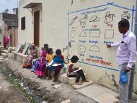 In this picture taken on August 27, 2020, Kalidas Chavdekar, a school teacher of Aasha Marathi Vidyalay points to a writing from textbooks of various subjects painted on the wall of a house to teach students who are unable to carry smartphones to attend online school classes amid Covid-19 coronavirus pandemic in Solapur, in Maharashtra state. AFP