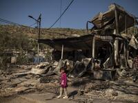 A girl stands amid rubbles in the burnt camp of Moria on the island of Lesbos after a major fire broke out, on September 9, 2020. Thousands of asylum seekers on the Greek island of Lesbos fled for their lives on September 9, 2020 as a huge fire ripped through the camp of Moria, the country's largest and most notorious migrant facility. Over 12,000 men, women and children ran in panic out of containers and tents and into adjoining olive groves and fields as the fire destroyed most of the overcrowded, squalid