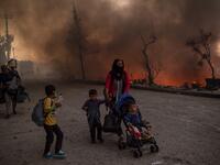 A woman and children flee flames major fire broke out in the Moria migrants camp on the Greek Aegean island of Lesbos, on September 9, 2020. 