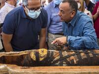 A picture taken on October 3, 2020 shows Egyptian Minister of Tourism and Antiquities Khaled Al-Anani (L), and Mustafa Waziri (R), Secretary General of the Supreme Council of Antiquities, unveil the mummy inside a sarcophagus excavated by the Egyptian archaeological mission working at the Saqqara necropolis, 30 kms south of the capital Cairo, which resulted in the discovery of a deep burial well with more than 59 human coffins closed for more than 2,500 years. They were unearthed south of Cairo in the spraw