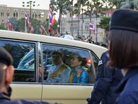 Thailand's Queen Suthida (C) and Prince Dipangkorn Rasmijoti (centre L) react inside a royal motorcade as it drives past a pro-democracy rally, as anti-government protesters (back) hold up their three-finger salute, in Bangkok on October 14, 2020. Teera NOISAKRAN / AFP
