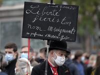 A man holds a placard reading "Liberty, I write your name by bleeding" as people gather in Strasbourg, eastern France, on October 18, 2020, in homage to history teacher Samuel Paty two days after he was beheaded by an attacker who was shot dead by policemen. FREDERICK FLORIN / AFP