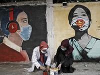Palestinian students dip their brushes as they paint murals of mask-clad girls in Gaza City on October 22, 2020, amid the novel coronavirus pandemic crises. Mohammed ABED / AFP