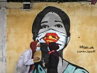 Palestinian students interact as they paint murals of a mask-clad girls in Gaza City on October 22, 2020, amid the novel coronavirus pandemic crises. Mohammed ABED / AFP