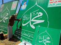 A Yemeni man adjusts the lights on a sign bearing the name of Islam's Prophet Mohammad and the portrait of Shiite Huthi rebel leader Abdul-Malik al-Huthi in the capital Sanaa on October 24, 2020, in response to comments by French President Emmanuel Macron defending cartoons of the Prophet Mohammed. Mohammed HUWAIS / AFP