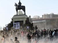 Demonstrators clash with riot police during a protest against Chilean President Sebastian Pinera's government on the constitutional referendum voting day at Plaza Italia square in Santiago on October 25, 2020. A year to the day after more than one million people thronged downtown Santiago in the biggest Chile's social uprising, Chileans vote Sunday on whether to change the country's dictatorship-era constitution seen as underpinning the nation's glaring inequalities. MARTIN BERNETTI / AFP