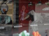 The image of a Palestinian student painting a large mural of a mask-clad girl is reflected on the doors of a shop in Gaza City on October 22, 2020, amid the novel coronavirus pandemic crises. (Instagram)