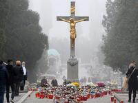 Faithfuls gather near the central cross, where candles have been laid, at the Mirogoj Cemetery in Zagreb, on November 1, 2020 to mark All Saints' Day. Every year on All Saints' Day, Croatian citizens visit and arrange the graves of their families. This year, due to the coronavirus pandemic, the usual crowds in cemeteries were absent, as citizens heeded the recommendation of the authorities to avoid mass gatherings. DENIS LOVROVIC / AFP