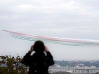 An onlooker takes a picture of the jets of the Italian Air Force aerobatic unit Frecce Tricolori (Tricolor Arrows) spreading smoke with the colors of the Italian flag as they fly over the city of Rome during the Armed Forces Day marking the end of World War I for Italy, on November 4, 2020. Filippo MONTEFORTE / AFP